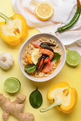 Bowl of spicy Thai soup on color background