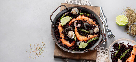 Black seafood Paella on gray background.