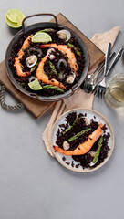 Black seafood Paella on gray background.