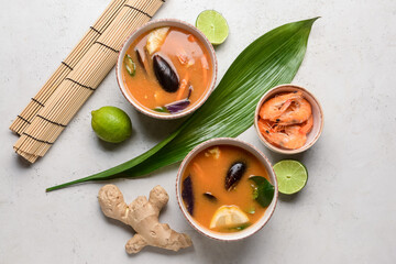 Fototapeta na wymiar Bowls of spicy Thai soup on light background