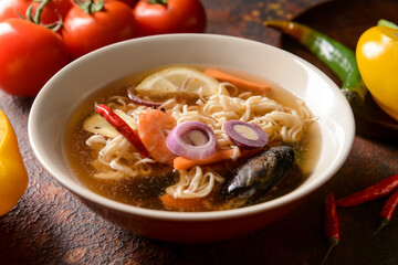 Bowl of spicy Thai soup on color background