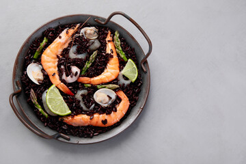 Black seafood Paella on gray background.