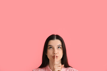 Young woman showing silence gesture on color background