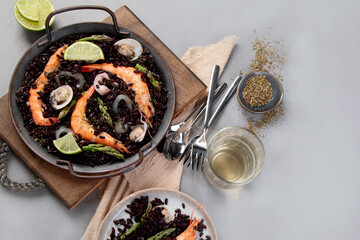 Black seafood Paella on gray background.