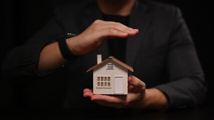 Close up view man hands protecting house model. Property insurance concept.