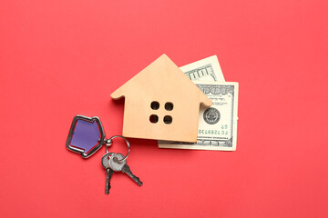 Wooden house with keys and banknotes on red background