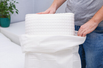 A man puts a pillowcase on an orthopedic pillow.