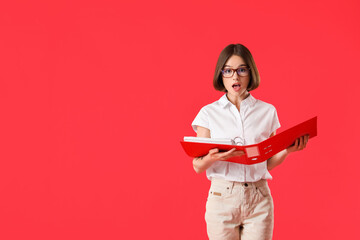 Surprised young woman with folder on color background