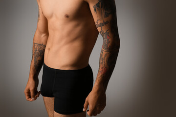 Handsome young man in underwear on grey background
