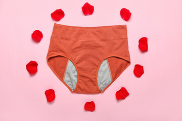 Composition with period panties and red rose petals on color background