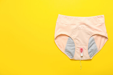 Period panties and used tampon on color background