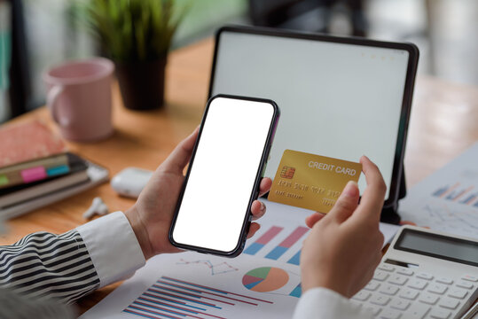 Close-up image of woman hands using smartphone blank white screen and holding credit card. Online shopping concept. Mock up.