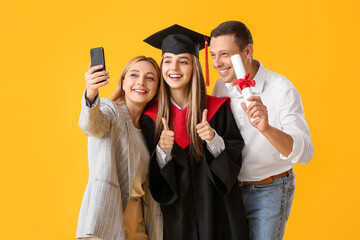 Happy female graduation student with her parents taking selfie on color background