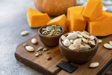 Raw superfoods pumpkin seeds after harvest. Pumpkin seeds in wooden bowl over gray stone background. Copy space.