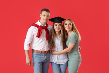 Happy female graduation student with her parents on color background