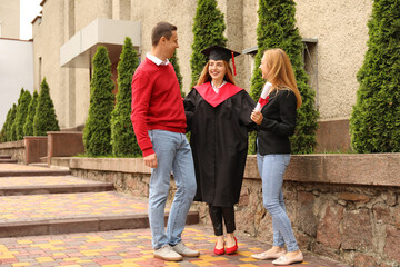 Fototapeta premium Happy young woman with her parents on graduation day