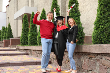 Happy young woman with her parents on graduation day