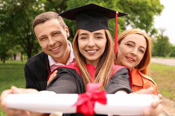 Happy young woman with her parents on graduation day