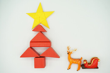 Christmas pentagram on yellow origami paper, red blocks to make a concept Christmas tree, moose with red sleigh. 