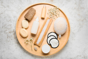 Wooden board with different bath supplies and flowers on light background