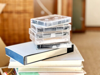 本の上に積み上げたビデオテープとカセットテープ - obrazy, fototapety, plakaty