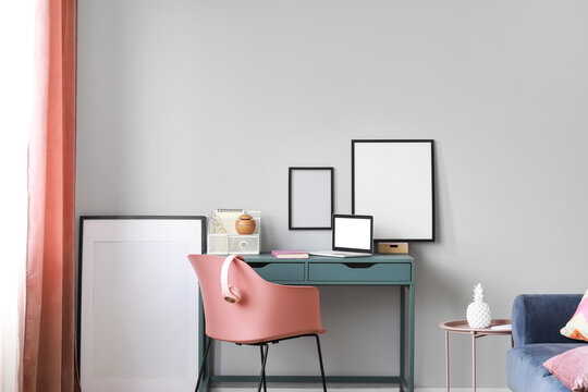 Interior of stylish room with modern workplace and blank frames