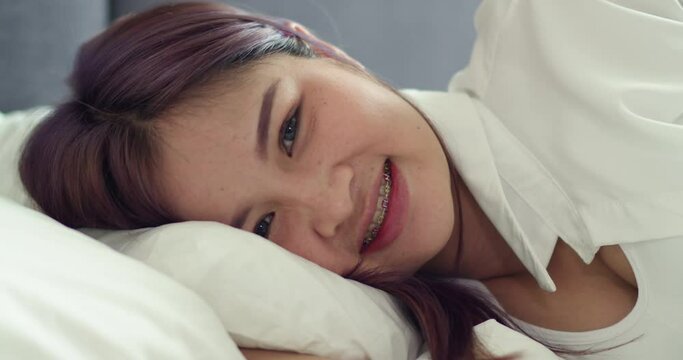 A beautiful Asian happy pregnant woman is lying on the bed and looking camera.