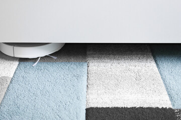 Washing Robot vacuum cleaner indoors cleans the flooring under the furniture. A device for cleanliness without wires.