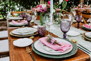 Table setup with flowers, glasses and plates on table decorated for Wedding Reception in terrace Latin America