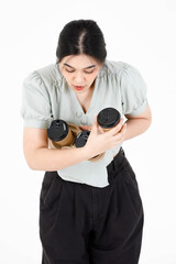 Portrait studio shot of Asian young clumsy teenager female model with ponytail hairstyle wearing casual outfit shocked and surprised when dropping disposable coffee cups holder on white background
