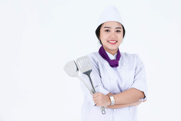 Portrait studio shot of Asian professional restaurant cooking female executive chef in cook uniform standing smiling look at camera holding spatula flipper turner crossed arms on white background