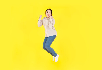 Portrait studio shot of Asian young happy female chubby plump model in casual outfit long sleeve shirt and denim jeans pants smiling look at camera jumping high exercise alone on yellow background