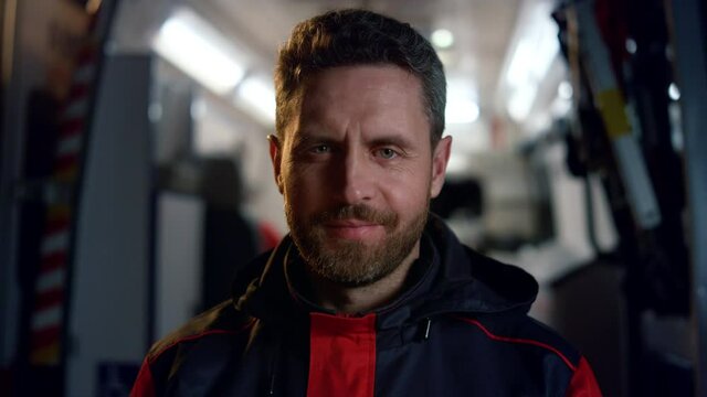 Medical worker looking at camera. Happy male paramedic standing on street