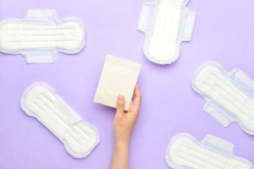 Female hand with menstrual pads on purple background © Pixel-Shot