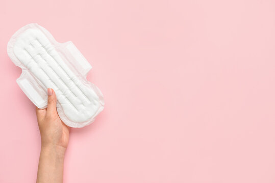 Female hand with menstrual pad on pink background