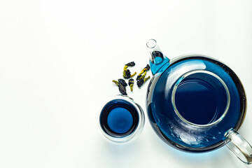 background with circles. Blue tea in glass cups and a glass teapot, white background, a place to copy. Butterfly pea flower tea is brewed in a glass teapot and served