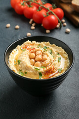 Bowl with delicious hummus on dark background, closeup