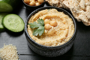 Bowl with delicious hummus on table, closeup