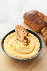 Bowl with delicious hummus and bread on table, closeup