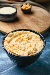 Bowl with delicious hummus on color background, closeup