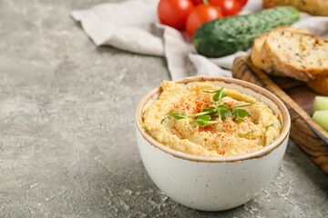 Bowl with delicious hummus on grey background, closeup