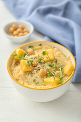 Bowl with delicious hummus and cheese on light wooden background, closeup