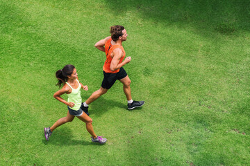 Runners running people healthy fitness couple jogging together on grass park view from above with...