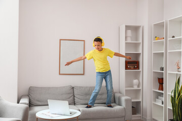 Funny little boy with laptop learning to dance at home