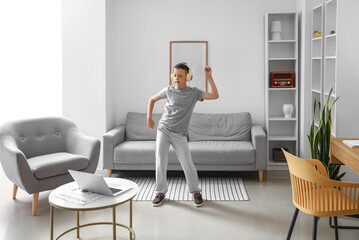 Funny little boy with laptop learning to dance at home © Pixel-Shot