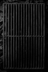Top view of black cast iron grate over cold coals on grill