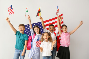 Happy pupils of language school near light wall with USA flag
