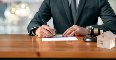Real Estate concept, judge gavel or lawyer in auction with house model. Businessman signing a contract..