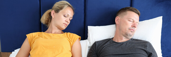 Tired man and woman sleep in bed with laptops closeup