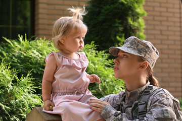 Upset female soldier with her baby girl outdoors